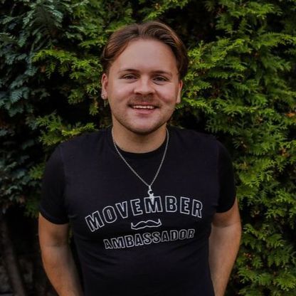 Photo of young man, wearing a short moustache, smiling to camera.